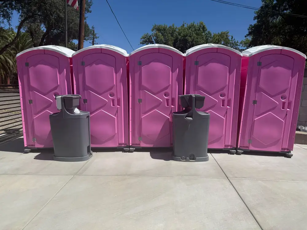 Row of pink event porta potties with two hand-washing stations