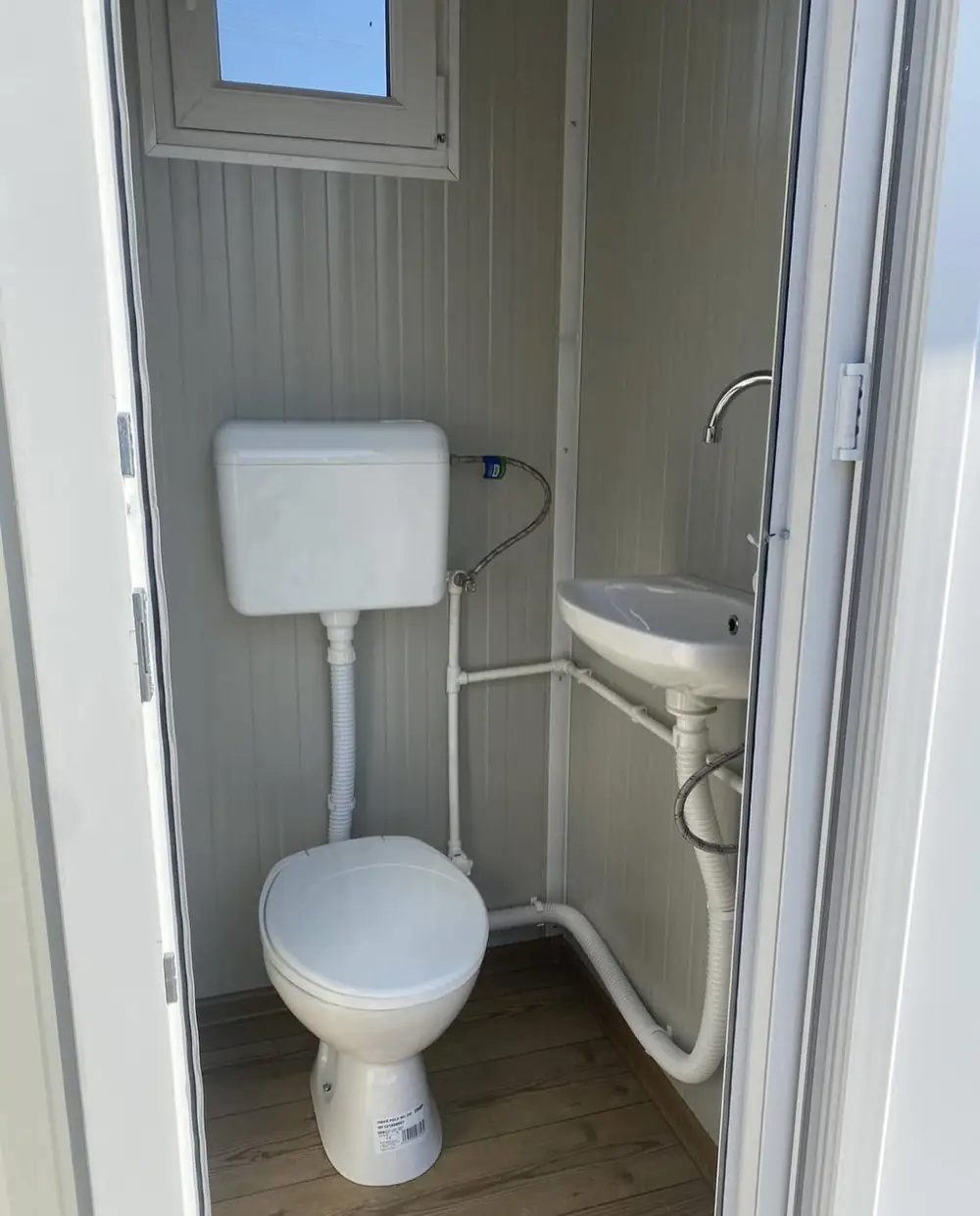 Flushing toilet and small sink inside a deluxe restroom cabin