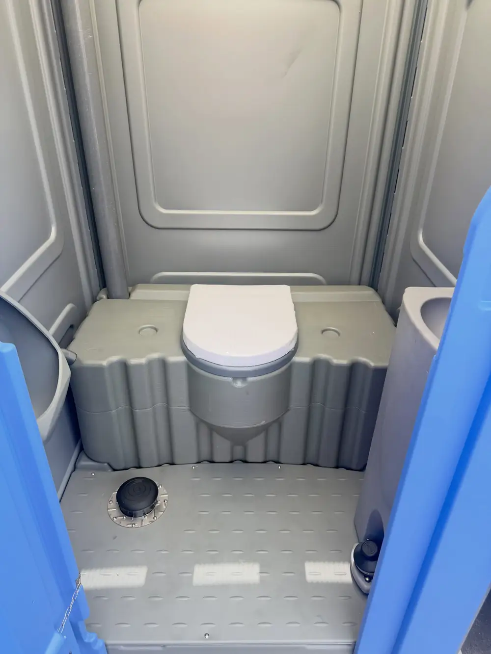 Clean grey interior of a porta potty with a molded toilet seat