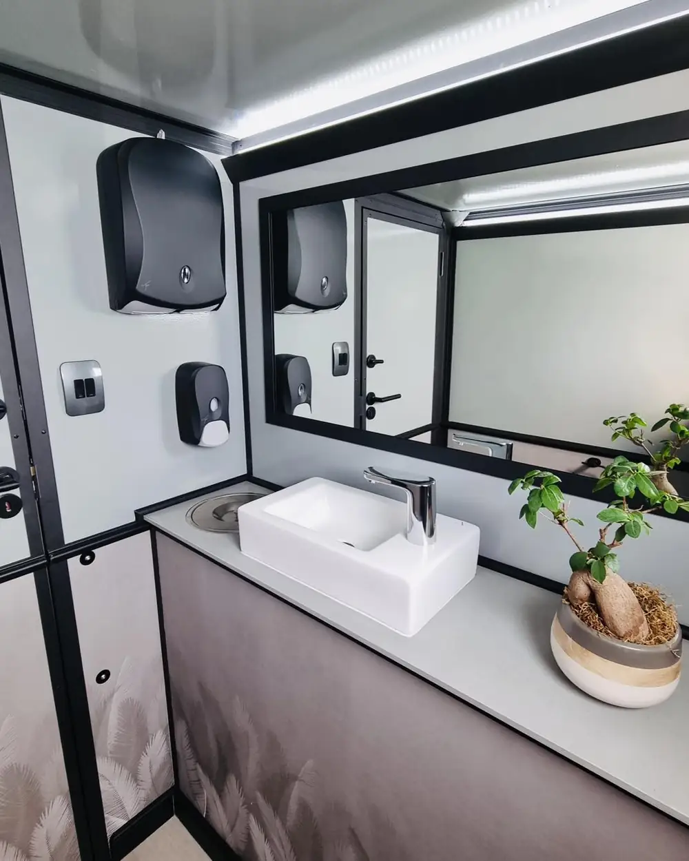 Restroom trailer vanity with mirror, soap and paper towel dispenser