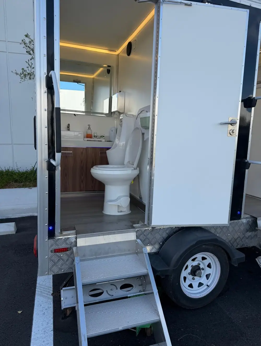 Restroom trailer stall with flushing toilet and warm lighting