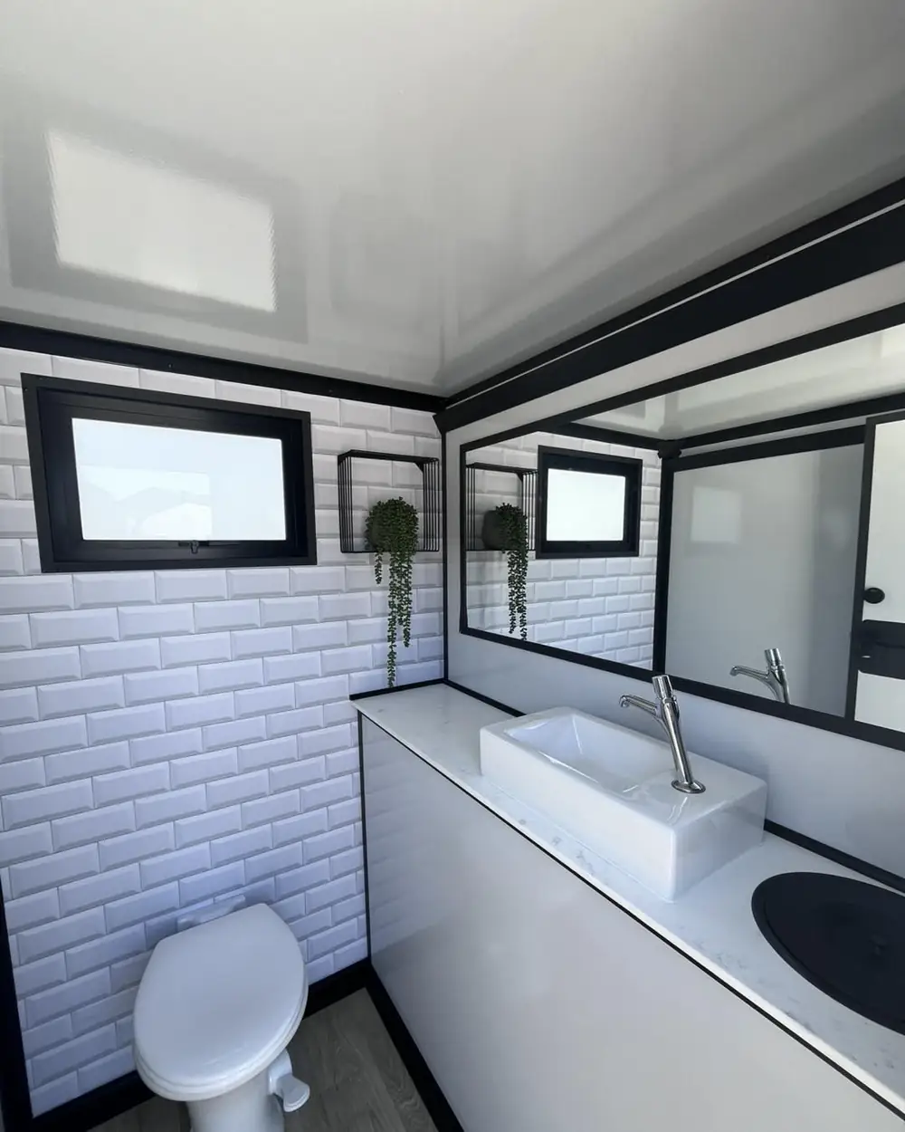 Tiled restroom trailer interior with mirror and sink