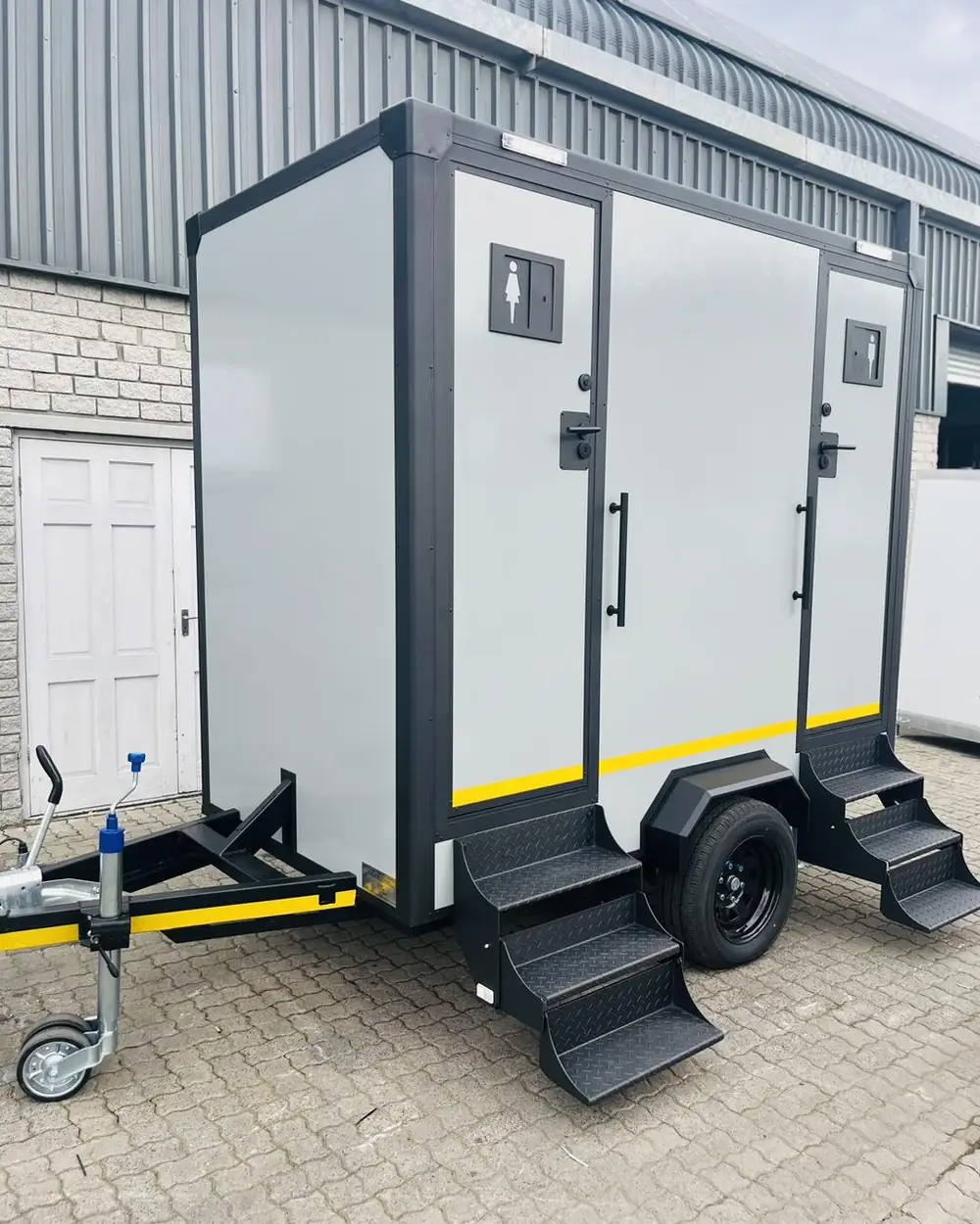Two-stall restroom trailer with separate doors and folding steps
